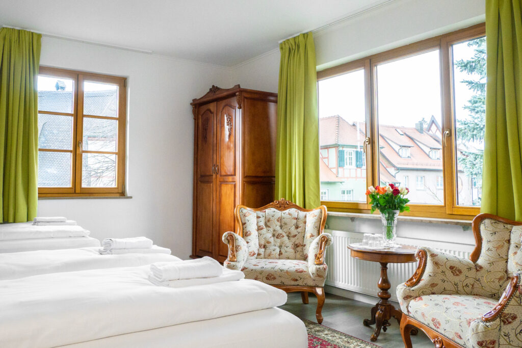 Zimmer 206 – Betten, Fenster und Sitzecke