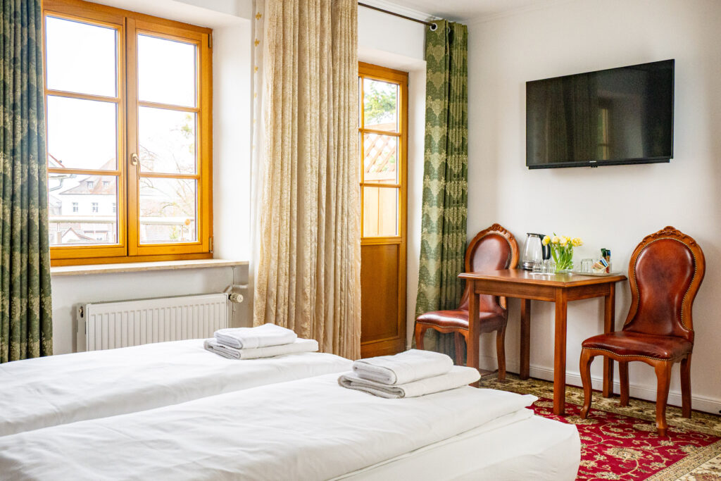 Zimmer 202 – Bett, Fenster, Tisch und Balkon