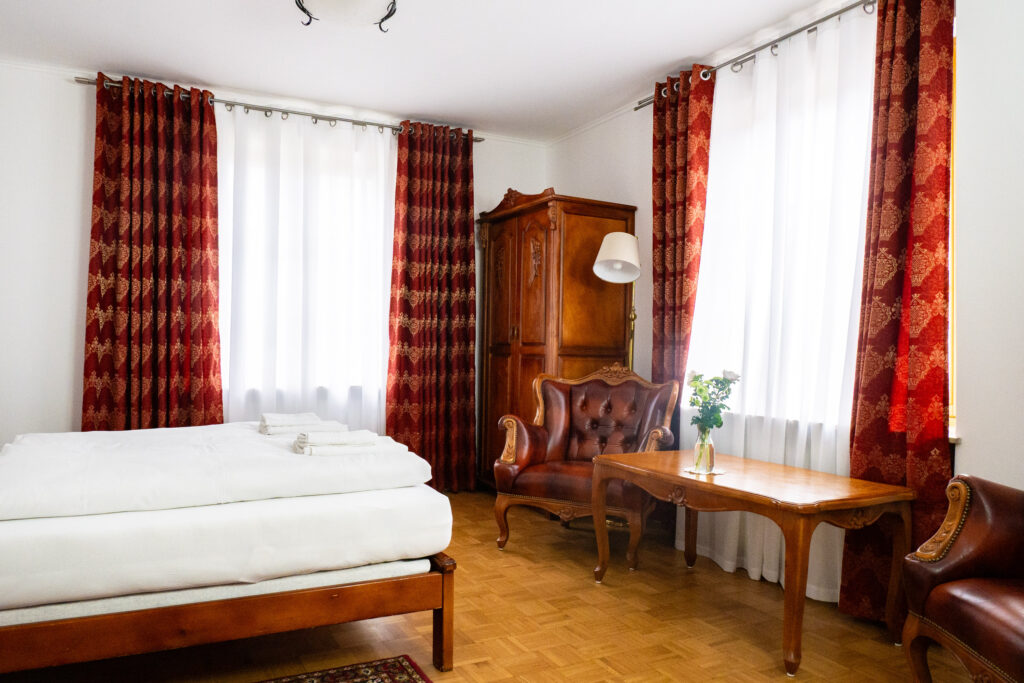 Zimmer 102 – Bett, Sitzecke und Fenster